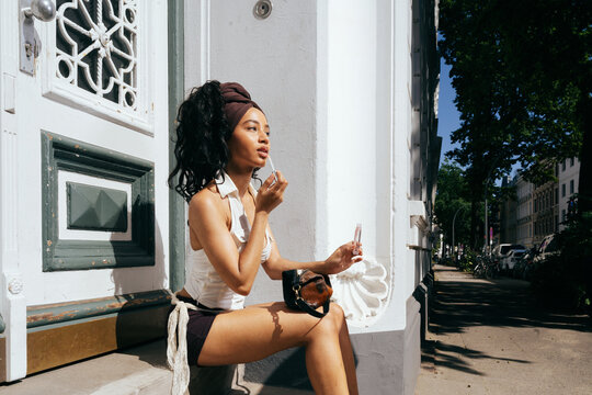 Woman Applying Lip Gloss Outdoors