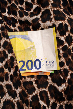 200 euro banknotes tucked into pocket of leopard print fabric garment
