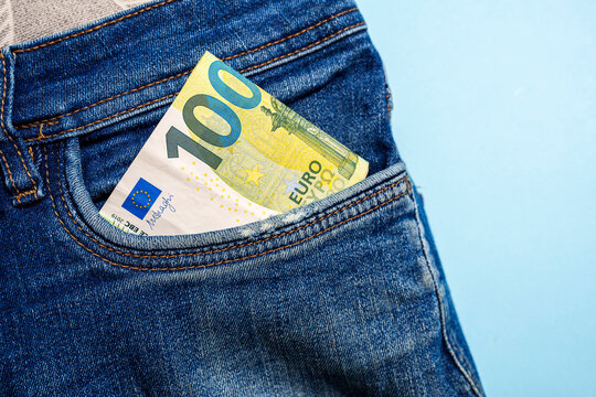 100 euro banknote in blue denim jeans pocket on blue background