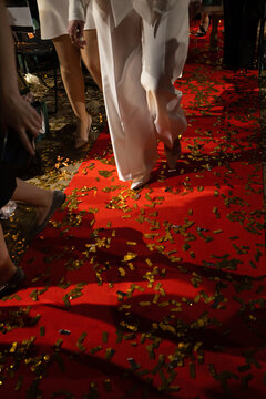 People walking on a red carpet covered with gold confetti. Concept of celebrity event, gala award ceremony and luxury celebration.