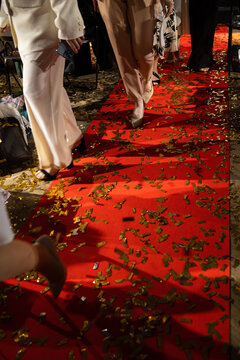 People walking on a red carpet covered with gold confetti. Concept of celebrity event, gala award ceremony and luxury celebration.