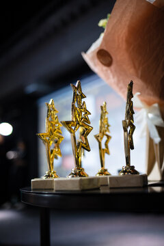 Golden star trophy awards on a dark blurred background. Concept of success, victory and recognition.