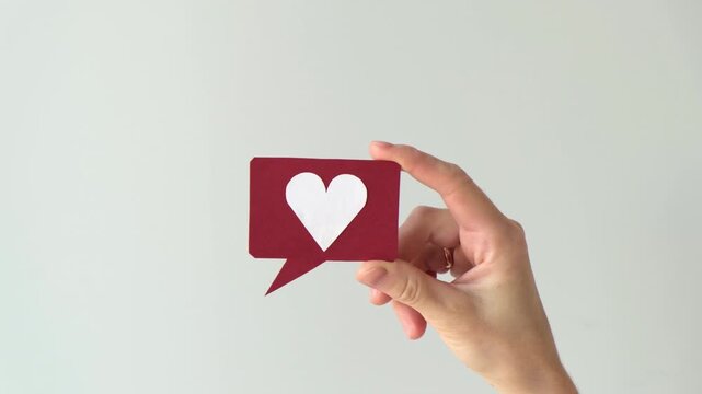 Social media and digital communication concept video featuring a hand holding a red speech bubble icon with a white heart symbol.