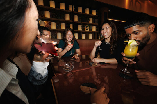 Diverse friends enjoying cocktails and drinks at bar