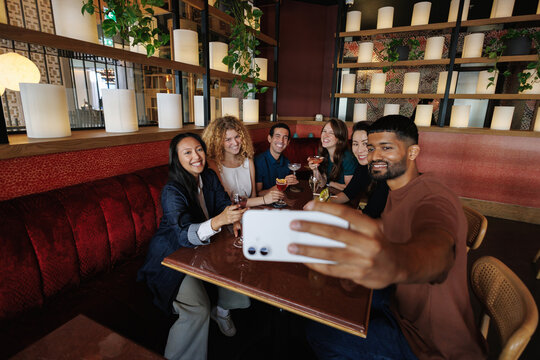 Diverse friends taking selfie celebrating in restaurant