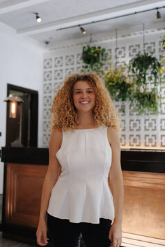 Young woman smiling with curly hair in modern indoor setting