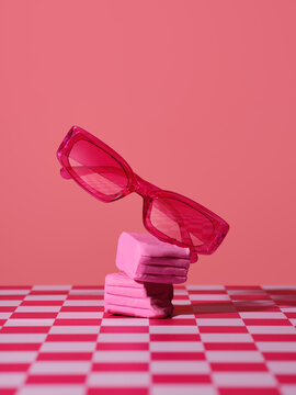 Vibrant pink rectangular sunglasses balanced on stacked pink