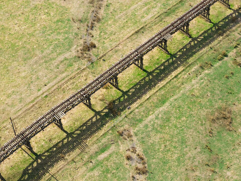 Abandoned railway bridge casting a shadow over farmland below