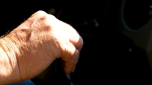 Elderly hand on a manual gear shift.