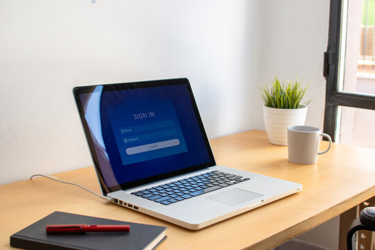 Computer login screen on laptop at wooden office desk