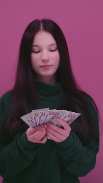 Girl is holding dollar bills in her hands. Woman has a stack of money. Ecstatic teen girl rejoicing success and holding lots of cash. Portrait young female with banknote