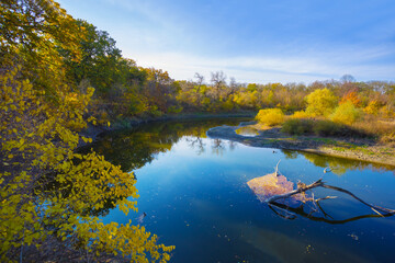 small river with red dry autumn forest on coast at the bright day © Yuriy Kulik
