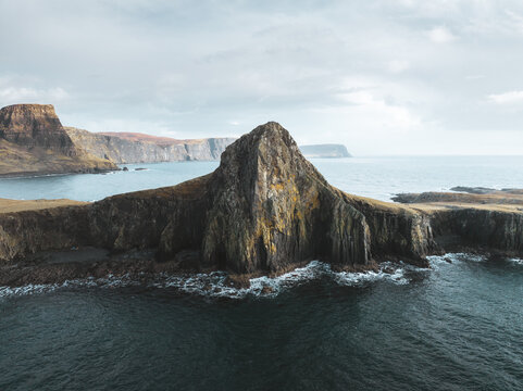 Aerial view of Neist Point, a dramatic rocky headland with steep cliffs and rugged terrain jutting into the sea, Isle of Skye, Scotland, United Kingdom.