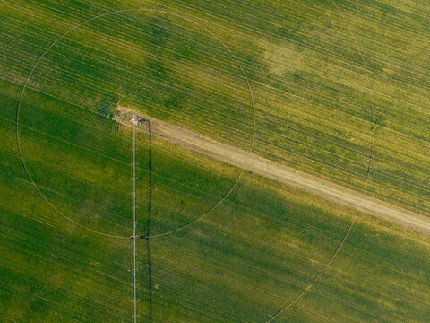 Aerial view of center pivot irrigation system in lush green agricultural fields, showcasing precision farming techniques and circular crop patterns. Nottingham Road, KwaZulu-Natal, South Africa.