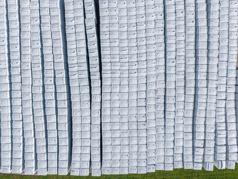 Aerial view of large quantities of compressed peat bales wrapped in white protective packaging and neatly stacked at the B-Peat processing facility in Krimulda Parish, Sigulda Municipality, Latvia.