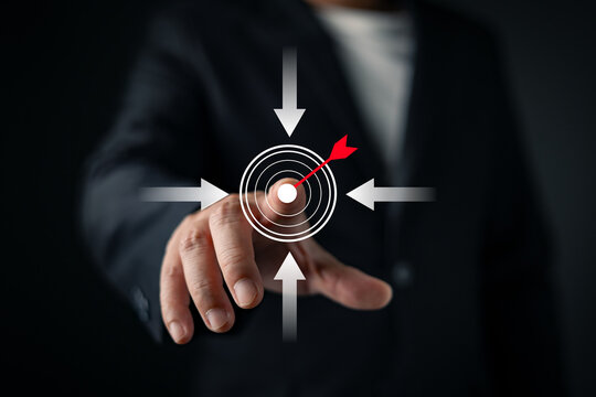 Businessman in suit touching target dartboard graphic with arrows, representing business goal, success strategy, and achievement. focusing on strategic planning.