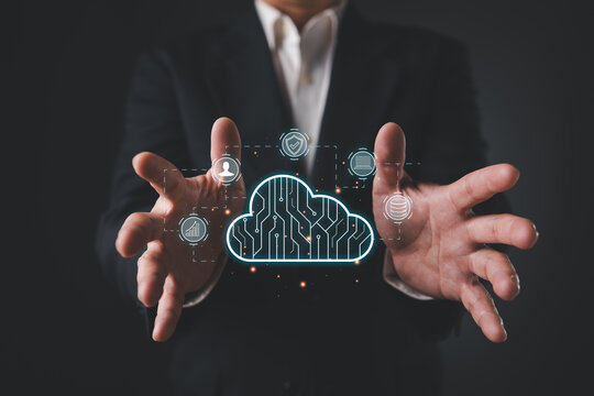 Business man in suit holding glowing cloud computing network with digital icons, representing data security, technology, and futuristic cloud storage solutions.