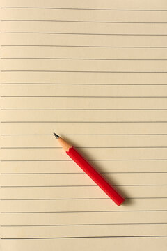 short red pencil on lined notebook paper background, taken from above, education concept with copy space