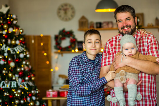 Happy family with a baby celebrating Christmas at home, enjoying cozy holiday moments together near a decorated Christmas tree in a warm festive atmosphere