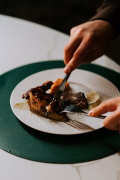 Cutting roasted chicken on a white plate during an elegant home dinner