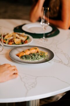 Gourmet salmon dinner served on a marble table at a restaurant during a relaxing evening date