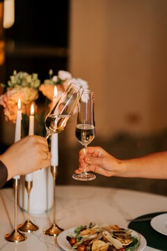 Couple toasting with glasses of champagne at a dinner table decorated with candles and fresh flowers