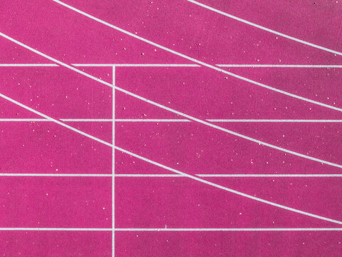 Aerial view of a vibrant pink running track with white lane markings, Latvia.