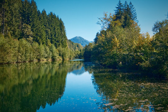Scenic view across the Weissach reservoir surrounded by green hills and forest in the Allg&auml;u region near Oberstaufen, Bavaria, Germany.
