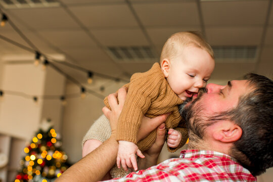 Happy family with a baby celebrating Christmas at home, enjoying cozy holiday moments together near a decorated Christmas tree in a warm festive atmosphere