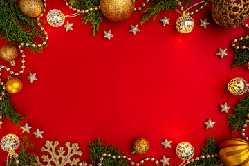 Obraz na płótnie Canvas Christmas frame with green fir branches, red baubles, golden stars, and glowing string lights on a red background. Ideal for holiday greeting cards, festive banners, and seasonal invitations.