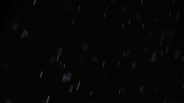 Dynamic macro motion blur of raining water droplets backlit on a solid black scene for weather simulation blending modes and creative video editing Background