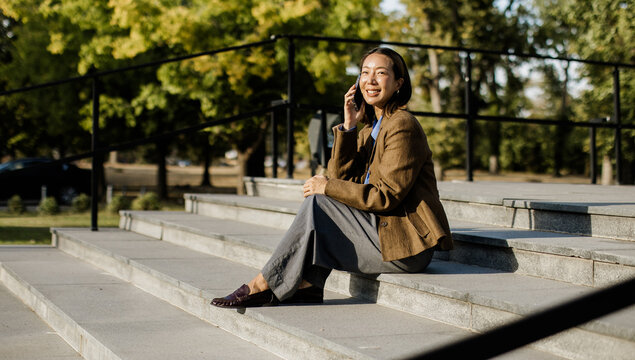 Korean woman enjoying a sunny day while talking on the phone outdoors