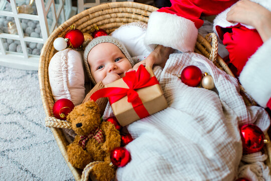 Cute baby and his teenage brother dressed as Santa Claus celebrating Christmas together at home in a cozy festive atmosphere.
