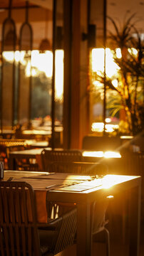 Warm golden hour sunlight streaming into a cozy restaurant dining area with empty tables