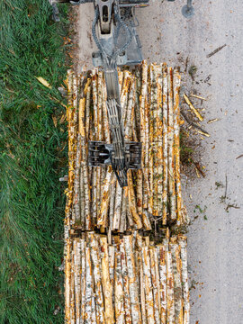 Aerial view of a logging truck equipped with a hydraulic crane loading cut timber logs onto its trailer at a forest logging site in Latvia.