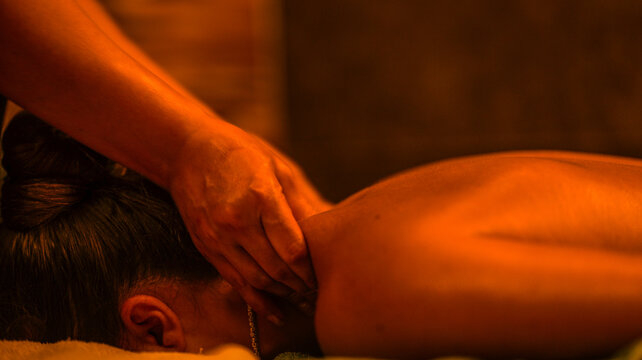 A professional therapist performs a relaxing neck massage in a warm and dimly lit spa environment