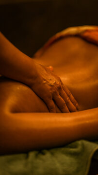 Professional therapist performing a relaxing back massage in a dimly lit wellness spa setting