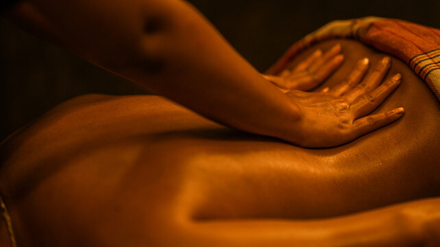 Professional therapist performing a relaxing back massage in a dim and tranquil spa environment