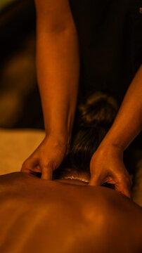 Professional therapist performing a relaxing neck and shoulder massage in a dim spa environment