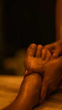 Professional foot massage session in a dimly lit spa environment with warm golden lighting