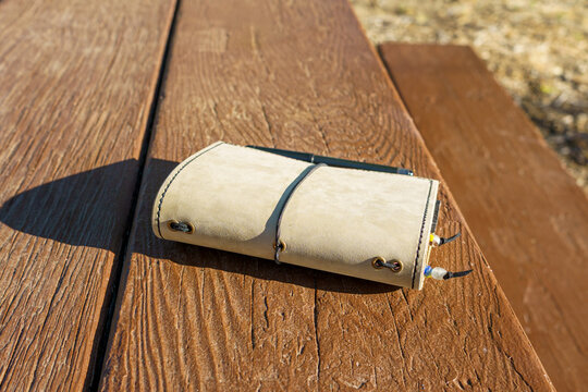 Suede leather nature journal on a wooden park bench table with copy space