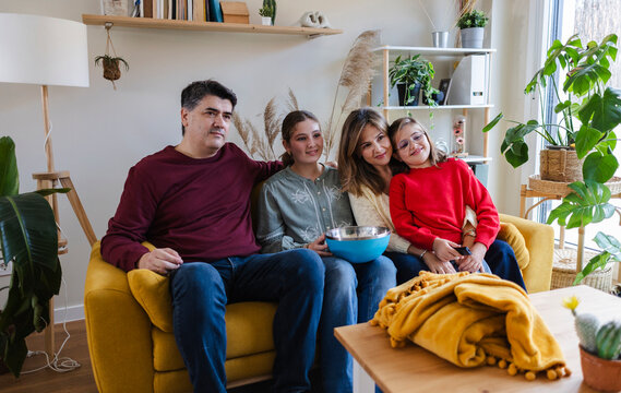 Family enjoying popcorn together watching movie at home