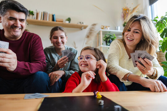 Family playing cards and board game laughing together at home