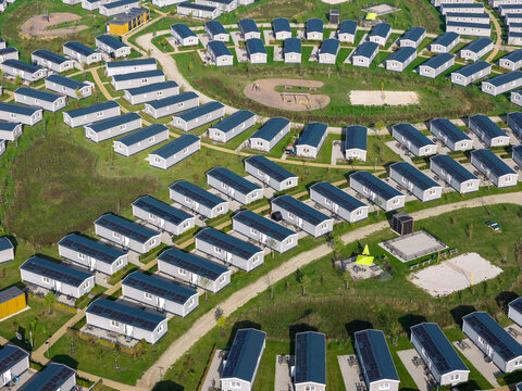 Aerial view of a holiday park featuring rows of modern mobile homes with solar panels on their roofs, surrounded by green lawns and pathways in The Netherlands.