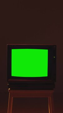 TV retro vintage television with green screen chroma key, old CRT TV with blank green screen for mockup standing in dark room with neon light, 80s 90s nostalgia