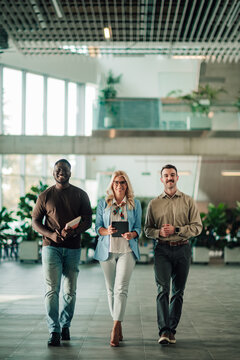 Diverse business people walking confidently in modern office building, collaborating on project development