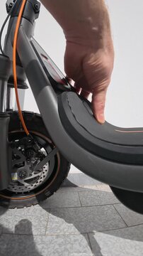 Close-Up of Person Inserting Charging Cable into Electric Scooter Port