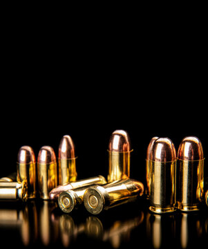 Shiny brass pistol bullets on black back