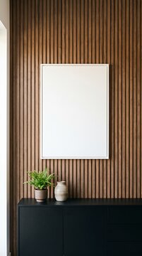 Minimal blank frame mockup on walnut slat wall above black sideboard with fern and ceramic vase
