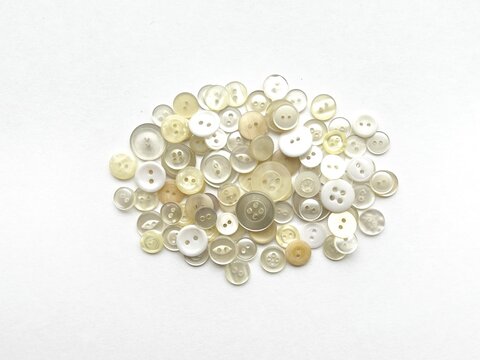 egg-shaped object made from button collage, three-dimensional oval shape made with buttons, plant seed-like shape made with buttons, simple shape, decorative illustration made with white buttons